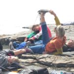 woman doing yoga on rocks by the sea