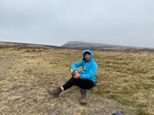 walker stretching her glute muscle on a mountain