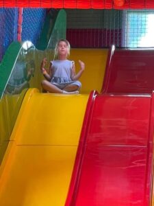 Young girl doing yoga on a colourful slide