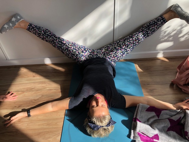 woman doing yin yoga pose against wall
